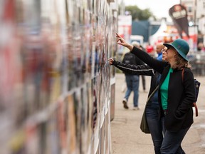 Visitors take in play posters at the Edmonton International Fringe Theatre Festival in Edmonton on Aug. 19, 2019.