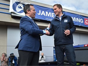 Conservative Leader Andrew Scheer shakes the hand of Alberta Premier Jason Kenney on the bed of a pickup truck while campaigning at candidate James Cumming's campaign office on Jasper Avenue in Edmonton on Saturday, Sept. 28, 2019.