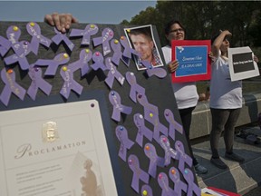 Jocelyn Willier from the AAWEAR team holds a sign in silence behind a board of purple ribbons pinned to the board as a memorial.   Edmonton's International Overdose Awareness Day event on the steps of the Alberta Legislature. File photo.