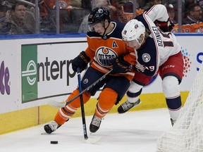 The Edmonton Oilers' Ryan Nugent-Hopkins (93) battles the Columbus Blue Jackets' Ryan Dzingel (19) behind the net during first period NHL action at Rogers Place, in Edmonton Thursday March 21, 2019.