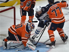 Winnipeg Jets Mark Latestu (22) pokes the puck from underneath Edmonton Oilers goalie Stuart Skinner (50) as Oscar Klefbom (77) tries to tie up Latestu during pre-season NHL action at Rogers Place in Edmonton, Monday, Sept. 16, 2019.