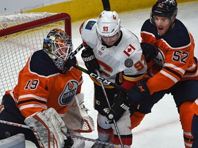 Edmonton Oilers Patrick Russell (52) and Calgary Flames Sam Bennett (93) can't get their sticks on the puck in front of goalie Mikko Koskinen (19) during pre-season NHL action at Rogers Place in Edmonton, September 20, 2019.