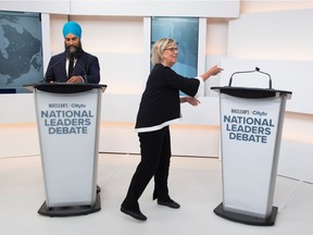 Green Party Leader Elizabeth May reaches to the empty mic stand where the invited Liberal leader and Prime Minister Justin Trudeau turned down an invitation to the Maclean's/Citytv National Leaders Debate, next to New Democratic Party (NDP) leader Jagmeet Singh on the second day of the election campaign in Toronto, Ontario, Canada Sept. 12, 2019.