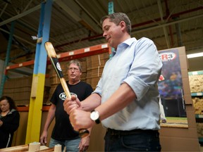 Conservative leader Andrew Scheer holds a maple baseball bat during a campaign stop at KR3 Bats in Cambridge, Ontario on September 24, 2019.