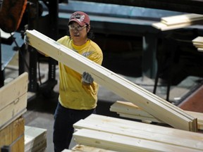 Workers cut and bundle up lumber at Spruceland Millworks in Acheson west of Edmonton. File photo.