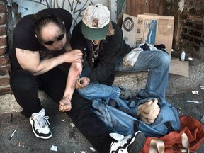 Drug addicts inject heroin on the back steps of the Washington Hotel in Vancouver's Downtown Eastside in 2017.
