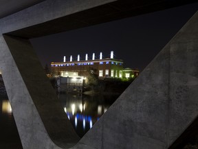 Rossdale Power Plant (right) is framed by the Walterdale Bridge, in Edmonton Thursday Oct. 17, 2019. The power plant is lit by 35 light stands in its mezzanine floor windows and 28 lights on its smoke stacks. Photo by David Bloom