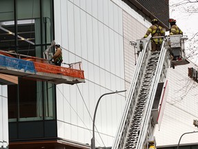 Edmonton Fire Rescue Service firefighters rescue one of two maintenance workers, (in white helmet) caught in a wind storm who were working on the Stantec tower in downtown Edmonton on Friday, Oct. 25, 2019. Environment Canada has issued a wind warning in Edmonton. Photo by Ian Kucerak/Postmedia