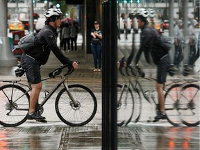 A cyclist rides on a cold and rainy day along Jasper Avenue past 101 Street in Edmonton, on Thursday, Sept. 26, 2019.