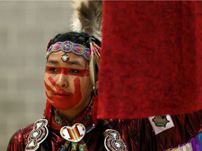 Jamie Medicine Crane helps hold aloft a red dress that memorializes missing and murdered Indigenous women and girls during the Sisters in Spirit Vigil at Boyle Street Plaza in Edmonton, on Friday, Oct. 4, 2019.