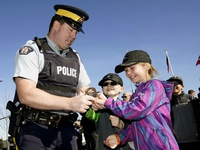 Parkland RCMP Constable Gordon Marshall puts the handcuffs on Alexandra and Declan Hobbs at the grand opening of the new Parkland RCMP detachment in Spruce Grove, Alberta on October 11, 2019.