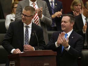 Alberta Finance Minister Travis Toews, left, is applauded by Alberta Premier Jason Kenney  after Toews delivered his budget speech at the Alberta legislature in Edmonton on Thursday, Oct. 24, 2019.