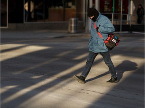 A pedestrian crosses into the sun at 101 Street at Jasper Avenue on a cold fall morning in Edmonton, on Tuesday, Oct. 29, 2019. The weather is expected to warm up as the week continues.