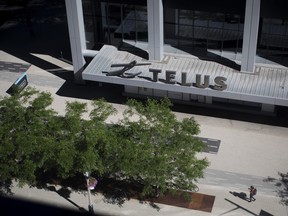 Pedestrians walk past the Telus Harbour building in Toronto on July 9, 2018.