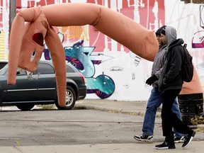 Pedestrians walk past a wacky inflatable tube man along Whyte Avenue near 99 street, in Edmonton Tuesday Oct. 8, 2019.