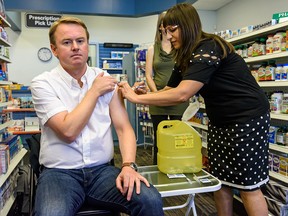 Health Minister Tyler Shandro receives a flu shot from pharmacist Anar Slueman at Southport Pharmacy in Calgary on Friday, Oct. 11, 2019. Influenza immunization clinics will start the week of Oct. 21 across Alberta.
