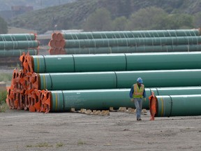 A workman walks past steel pipe to be used in the oil pipeline construction of the Trans Mountain expansion project at a stockpile site in Kamloops, British Columbia. File photo.
