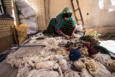 A village rugmaker hand ties the wool knots that hold the rug together for generations.