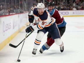Connor McDavid #97 of the Edmonton Oilers fights for the puck against Samuel Girard #49 of the Colorado Avalanche in the first period at the Pepsi Center on Nov. 27, 2019, in Denver, Colorado.