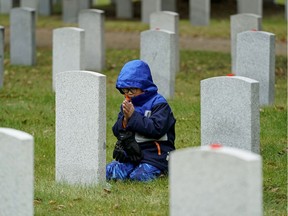 Aiden Pham (7-years-old) kneels in prayer in front of a war veteran's headstone on Monday November 4, 2019. Hundreds of  students from Edmonton area schools attended the 9th annual No Stone Left Alone remembrance ceremony at Beechmount Cemetery in Edmonton. The annual commemoration ceremony is held every November to honour the sacrifice and service of Canada's military by education students and placing poppies on the headstones of war veterans.