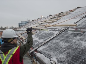 Colin Johnston of Bird Construction clears snow off some of the newly installed panels on Thursday, Nov. 28, 2019. Solar panel installation on the roof of the Edmonton Convention Centre will reduce electricity costs by more than $200,000 per year once the panels are online.