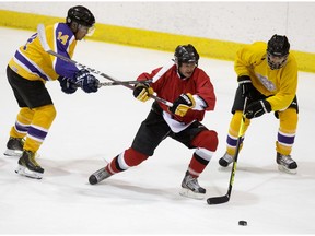 Crown prosecutor players in yellow battle a defence lawyers team player during the sixth annual Crown vs. Defence Hockey Classic at Clare Drake Arena in Edmonton on Saturday Nov. 30, 2019.