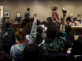Catholic school board trustees walk out of a board meeting Tuesday as supporters of Una Momolu raise their fists in the air, in Edmonton Tuesday Nov. 26, 2019.