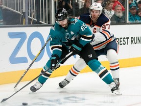 Nov 12, 2019; San Jose, CA, USA; San Jose Sharks defenseman Erik Karlsson (65) and Edmonton Oilers center Connor McDavid (97) battle for possession in the first period at SAP Center at San Jose. Mandatory Credit: John Hefti-USA TODAY Sports ORG XMIT: USATSI-405273