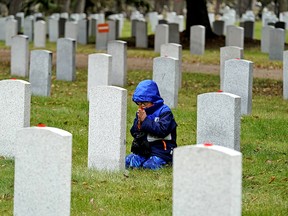 Aiden Pham (7-years-old) kneels in prayer in front of a war veteran's headstone on Monday November 4, 2019. Hundreds of students from Edmonton area schools attended the 9th annual No Stone Left Alone remembrance ceremony at Beechmount Cemetery in Edmonton. The annual commemoration ceremony is held every November to honour the sacrifice and service of Canada’s military by education students and placing poppies on the headstones of war veterans.