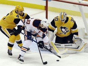 Edmonton Oilers center Ryan Nugent-Hopkins (93) battles for the puck against Pittsburgh Penguins defenseman Justin Schultz (4) and goaltender Matt Murray (30) during the second period at PPG PAINTS Arena.