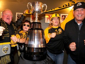 Tiger Cats fans Jim Cimba, Besty Paterson, Sandy Shields and Leo Ezerins, CFL Alumni Association Executive Director, pose by around the Grey Cup and cheer for a photo during the Canadian Football Hall of Fame Reception in the Scotiabank Saddledome Saturday, November 23, 2019.