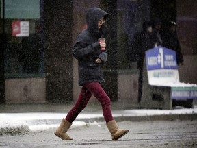 A woman scurries across the street in downtown Edmonton on Wednesday December 4, 2019. Snow and temperatures around -2C are forecast for the day.