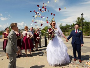 Alex Panas, 12, throws flower petals into the air during the marriage of Marni Panas and Kate Beneteau at Patricia Lake Park in Edmonton, on Sunday, June 30, 2019.