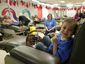Emmett Hodge, four-years-old, and his mother Amber (seated) were handing out candy canes to blood donors at the Canadian Blood Services donor clinic in Edmonton on Thursday, Dec. 19, 2019.