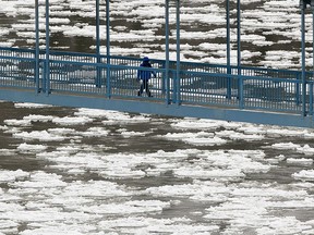 A pedestrians walks across the Dudley B. Menzies Bridge as ice begins to form below on the North Saskatchewan River, in Edmonton Friday Nov. 29, 2019.