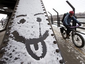 A cyclist makes their way past a face drawn in the snow, as they make their way across Edmonton's High Level Bridge, Monday Dec. 9, 2019.
