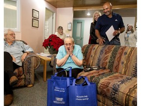 Joyce Jarrett-Mercer, seated, reacts as Grant Fuhr makes a special surprise delivery to the Viselka Seniors Home, 11415 86 St., as part of the London Drugs Stocking Stuffers for Seniors program in Edmonton on Monday, Dec. 16, 2019. All Jarrett-Mercer had requested was an autographed Grant Fuhr picture.
