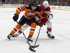 Edmonton Oilers defenceman Caleb Jones, left, battles the Carolina Hurricanes' Warren Foegele during NHL action at Rogers Place on Jan. 20, 2019.