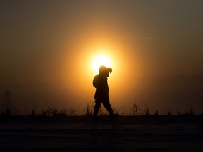 A pedestrian walks along 101 Avenue near 95A street as the Sun rises through a heavy icy fog, in Edmonton Wednesday Jan. 15, 2020.