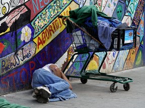 A man sleeps on the sidewalk outside the Boyle Street Community Services building in downtown Edmonton on July 31, 2019.