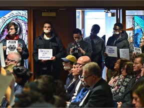 Protesters hold up signs with their mouths taped during a peaceful demonstration as  at the beginning of the Edmonton Catholic Schools board meeting on Tuesday, Jan. 28, 2020.