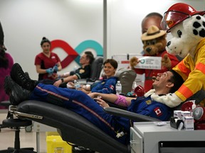 STARS flight paramedic Emerson North gets a massage from Edmonton Fire Rescue Services mascot Sparky while donating blood at the Canadian Blood Services clinic in Edmonton on Thursday, Jan. 16, 2020. Emergency service workers in Edmonton and area are part of this year's Sirens for Life campaign and are encouraging people to donate blood in January and February to support their campaign.