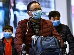 A traveller wears a mask, after arriving on a direct flight from China at Vancouver International Airport in Richmond, B.C., Jan. 24, 2020.
