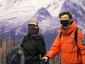 Passengers wear masks as they arrive at the international arrivals area at the Vancouver International Airport in Richmond, B.C. on Jan. 23, 2020.
