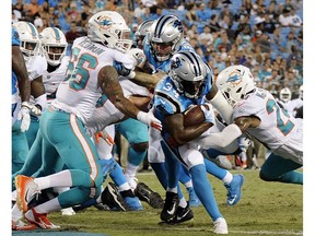 Carolina Panthers' Cameron Artis-Payne (34) runs through Miami Dolphins' Quincy Redmon (66) and Torry McTyer (24) for a touchdown in the second half of a preseason NFL game in Charlotte, N.C., in this file photo from Aug. 17, 2018.