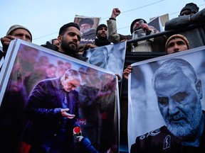 Protesters shout slogans against the United States and Israel as they hold posters with the image of top Iranian commander Qasem Soleimani, who was killed in a U.S. airstrike in Iraq, and Iranian President Hassan Rouhani during a demonstration in the Kashmiri town of Magam on Friday.