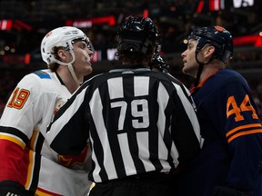 Forwards Matthew Tkachuk of the Calgary Flames, left, and Zack Kassian of the Edmonton Oilers are separated by a referee during NHL action on Dec. 27, 2019, at Edmonton's Rogers Place.