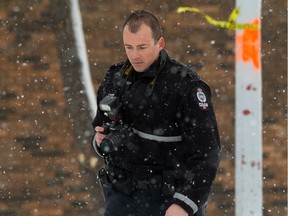 An Edmonton Police Service officer investigates a shooting where a woman was hurt and sent to hospital at the Richfield townhomes near 78 Street and 37 Avenue in the Mill Woods neighbourhood of Edmonton, on Saturday, Feb. 29, 2020.