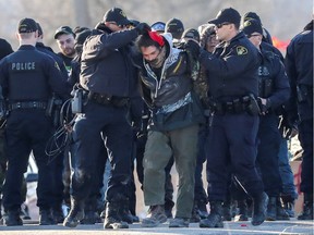 Police officers make an arrest during a raid on a Tyendinaga Mohawk Territory camp next to a railway crossing in Tyendinaga, Ontario, Canada February 24, 2020.