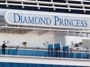 A passenger wearing a mask stands on the deck of the cruise ship Diamond Princess, as the vessel's passengers continue to be tested for coronavirus, at Daikoku Pier Cruise Terminal in Yokohama, south of Tokyo, Japan February 13, 2020.